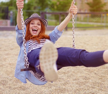 Eine Frau schaukelt und schaut dabei sehr freudig offen in die Kamera
